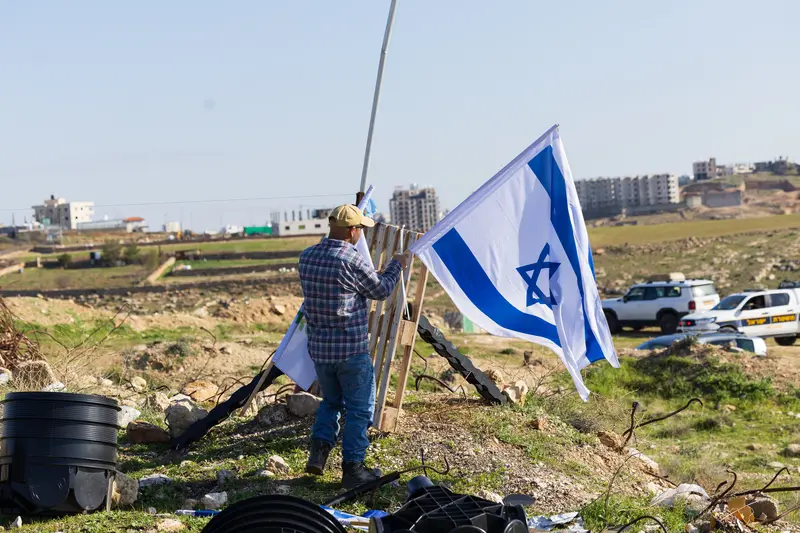 תושב מניף דגל ישראל גדול על תורן ביישוב