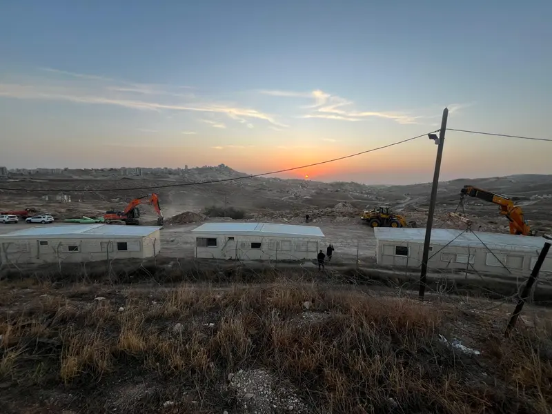 זריחה מעל שלושת הקרוואנים הראשונים וכלי העבודה על הגבעה