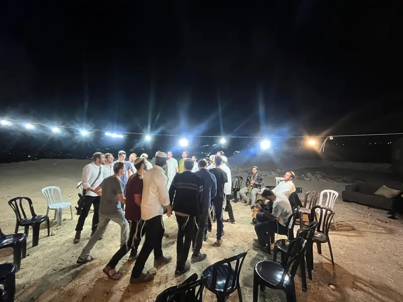 תושבים רוקדים במעגל תחת זרקורים בלילות הראשונים של העלייה לקרקע
